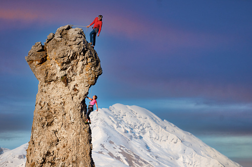 Male and female rock climbers with the lead that secures the partner