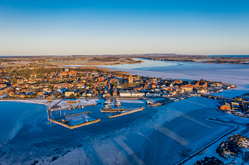 Drone’s eye’s view of the town of medieval town of Stege in Denmark surrounded by the frozen Baltic Sea during the winter of 2021.  Photographed in the late afternoon light, colour, horizontal format with some copy space.