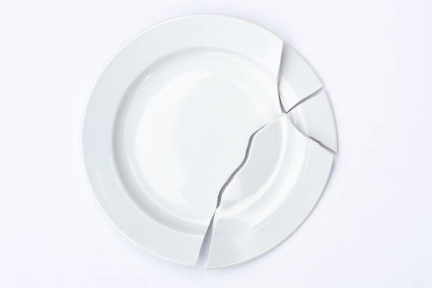 shards of a broken white plate stacked together on a white background. the concept of breaking up relations, divorce, destruction - divided plate imagens e fotografias de stock