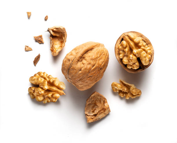 a whole walnut and an open walnut a whole walnut and an open walnut on a white table, top view walnut photos stock pictures, royalty-free photos & images