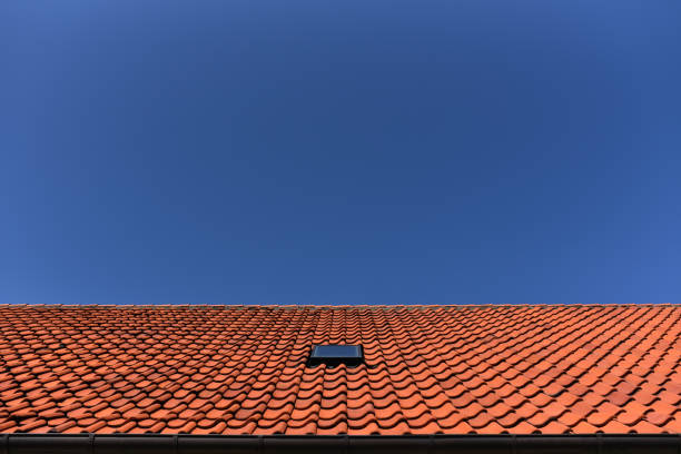 tile roof of house with window attic against the blue sky