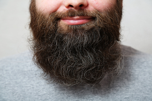 The bearded man laughs. Lips, nose, the mouth of a bearded man, close-up. A well-groomed, thick, beautiful beard. Close-up.