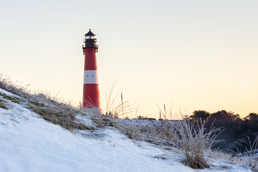 Lighthouse Hörnum at Sylt Island in Germany during golden hour directly after sunrise at an snowy winter morning
