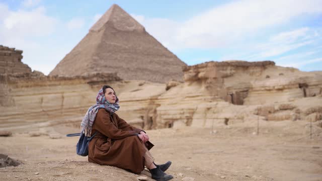 Woman sitting in the desert near the Giza pyramids