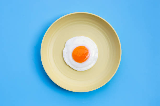 istock Fried egg in yellow dish on blue background. 1304257118