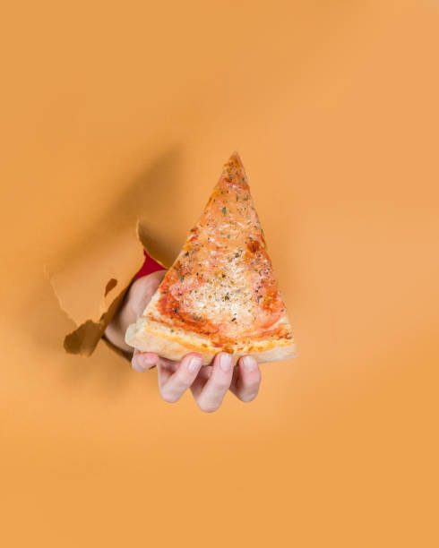 istock Hand from the background holds a slice of pizza. Torn background concept 1304258043