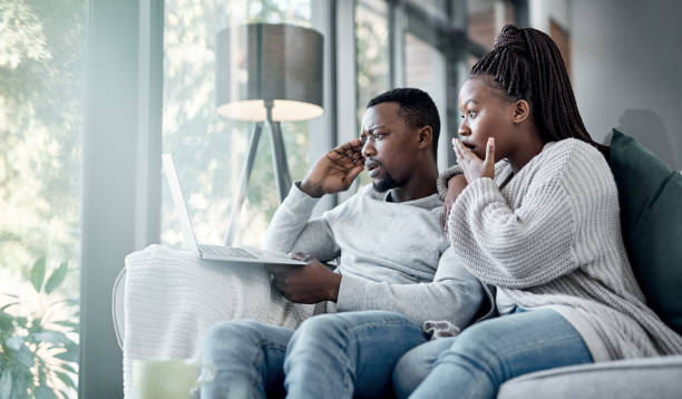 Who doesn't love a good old soapie now and then? Shot of a young couple using a laptop together on the sofa at home unusual couple stock pictures, royalty-free photos & images