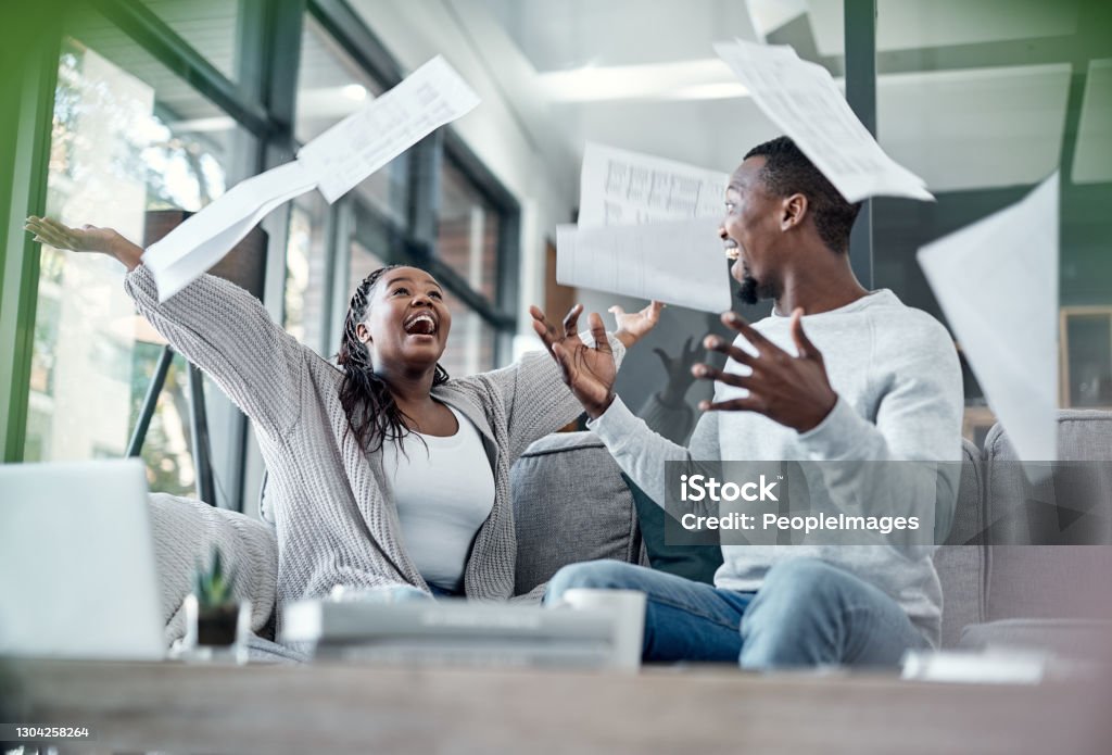 Fortune side with the financially free Shot of a young couple celebrating while going through paperwork at home Freedom Stock Photo