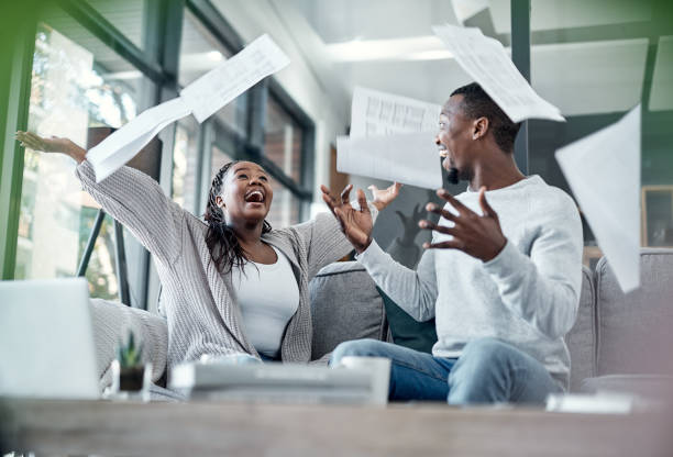 Fortune side with the financially free Shot of a young couple celebrating while going through paperwork at home debt stock pictures, royalty-free photos & images