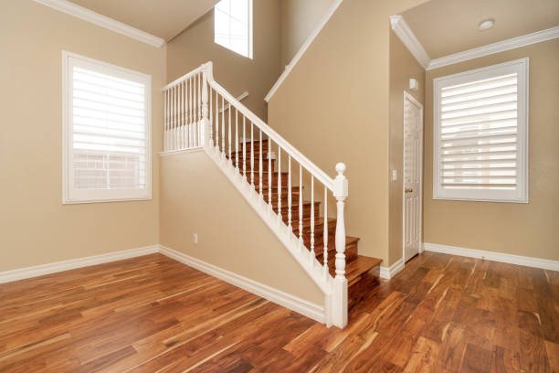 istock Large empty room with wood floor, molding and windows and stairs 1304259077