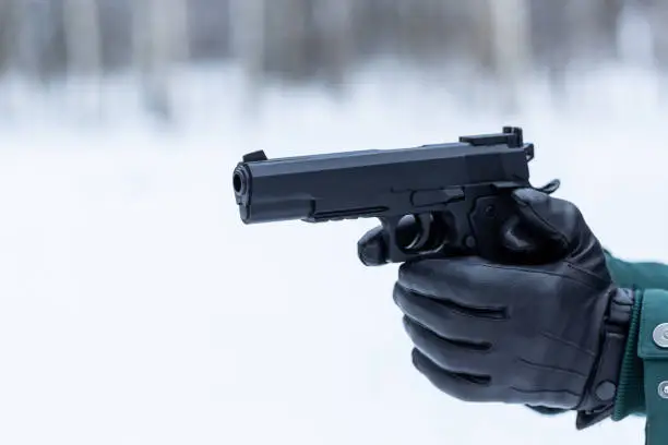 Photo of Black leather gloves with a pistol