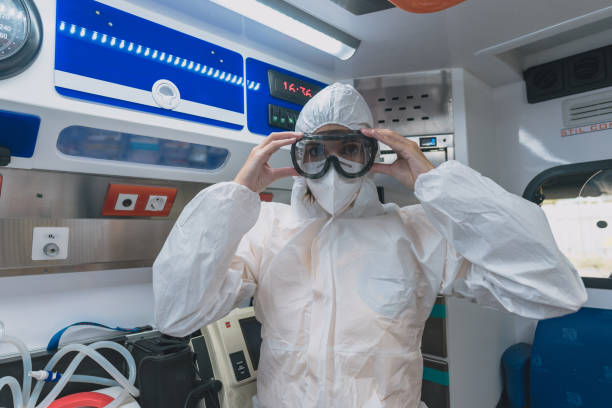young sanitary woman puts on a protective suit against viruses in an ambulance stock photo
