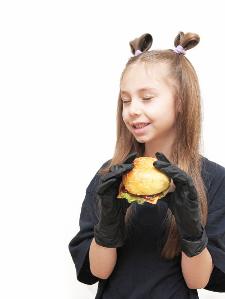 Cute little girl with black gloves eats hamburger.