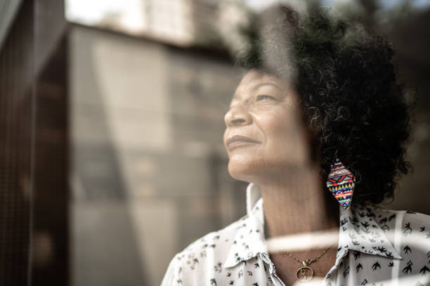 istock Senior woman looking through the window at home 1304263425