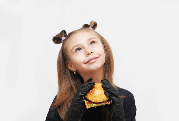 Cute little girl with black gloves eats hamburger.