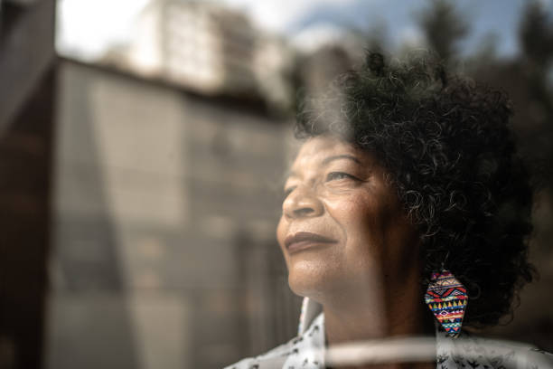 istock Senior woman looking through the window at home 1304263504
