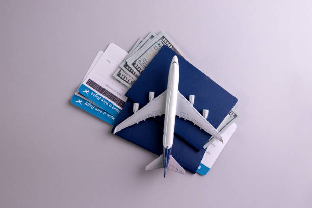istock Booking flight concept backdrop with airplane model, passports, money, and boarding pass documents on the grey background 1304264615