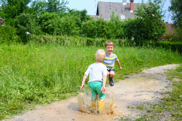 istock Two boys jumping in puddles of mudd 1304265896