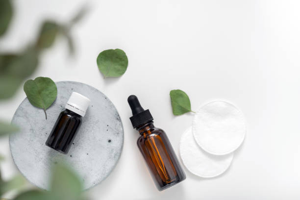 istock Essential oil with eucalyptus branches and cotton pads on white background with copy space top view. Brown glass cosmetic bottle, serum. 1304265897