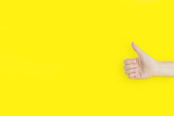 istock Showing thumbs up on yellow background - closeup shot. 1304267143