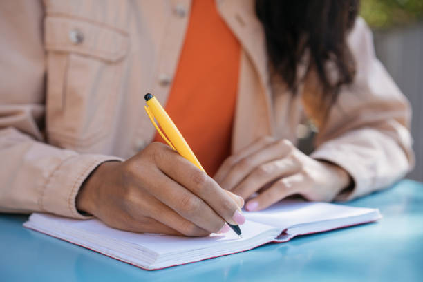 istock Closeup shot of university student hand holding pen, writing in notebook, studying 1304268631