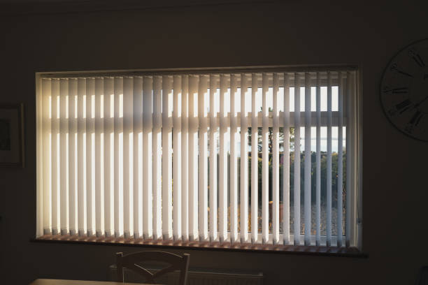 istock White vertical blinds on a window with bright sunlight behind them. there are slightly open. 1304269780