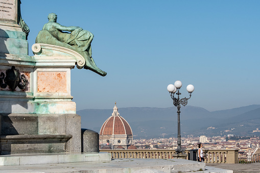 Florence, Italy - November 9, 2020: the Dome of the Florence Cathedral with a detail of the base of the statue of David in the foreground.