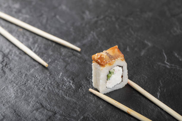 istock Single dragon sushi roll with chopsticks on black background 1304271547