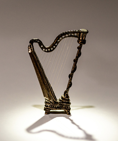 A small bronze harp, made at the end of the 19th century, differently illuminated casts suggestive shadows and lights.
