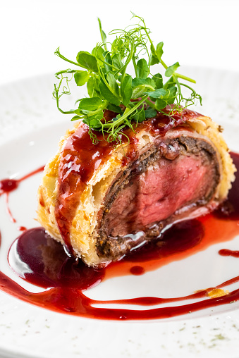 wellington beef with sauce on a plate on a white background in London, England, United Kingdom