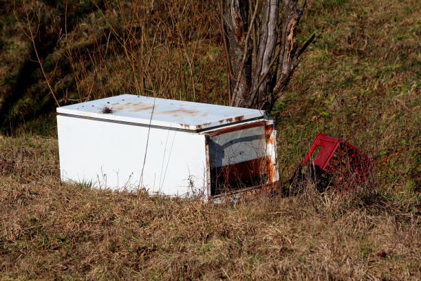 istock Broken destroyed large partially rusted white refrigerator dumped in nature as illegal garbage next to plastic beer crate 1304283020