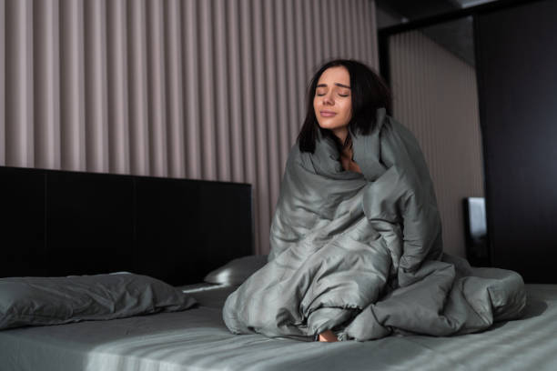 istock Womant r covers with large blanket sitting on bed 1304283197