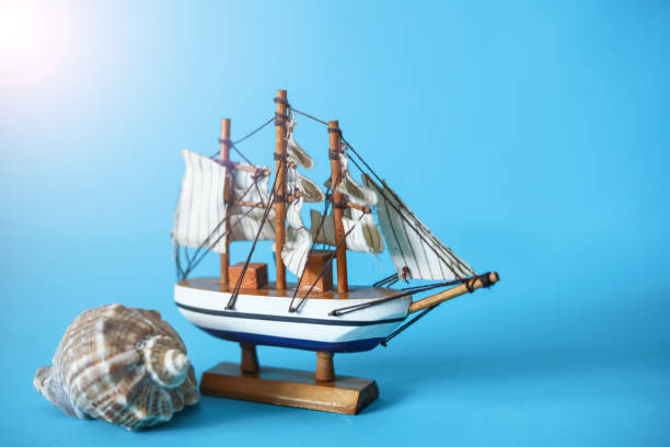 istock Sea Shell And Toy Ship Model Stands Blue Background 1304283922