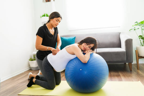 bela doula esfregando as costas de uma mulher grávida - human pregnancy massaging midwife prenatal care - fotografias e filmes do acervo