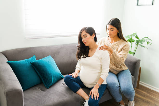 calma grávida mãe relaxando com uma massagem no ombro de sua parteira - human pregnancy massaging midwife prenatal care - fotografias e filmes do acervo