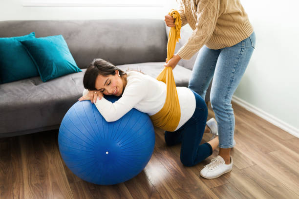 mulher grávida relaxando enquanto uma parteira embrulha um rebozo em sua barriga - human pregnancy massaging midwife prenatal care - fotografias e filmes do acervo