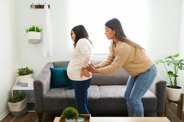 grávida mãe recebendo uma massagem de sua doula em casa - human pregnancy massaging midwife prenatal care - fotografias e filmes do acervo