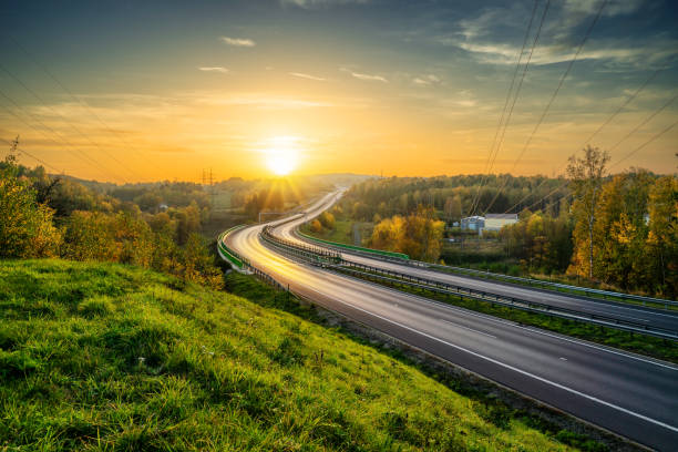 istock Empty asphalt highway winding through forested landscape in autumn colors at sunset 1304288198