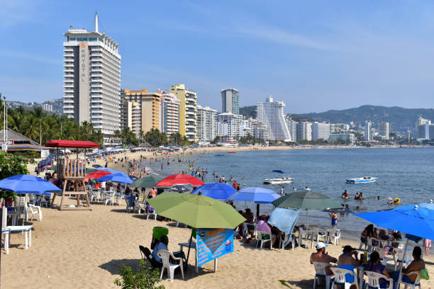 una foto della spiaggia di papagayo, può vedere turisti e hotel. - acapulco mexico sunset day foto e immagini stock