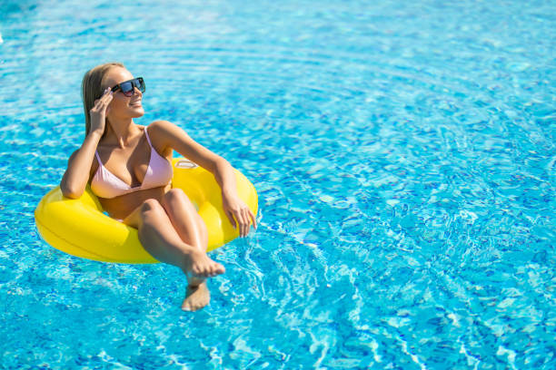 istock Happy young woman in bikini float with yellow rubber inflatable ring, playing and having a good time at water fun park pool, on a summer hot day 1304291025