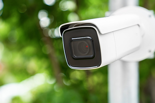 CCTV camera is installed in the garden with blur green tree background for monitor and safety system control around that area.