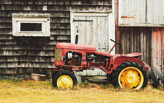 A 1940's era tractor beside a neglected barn.