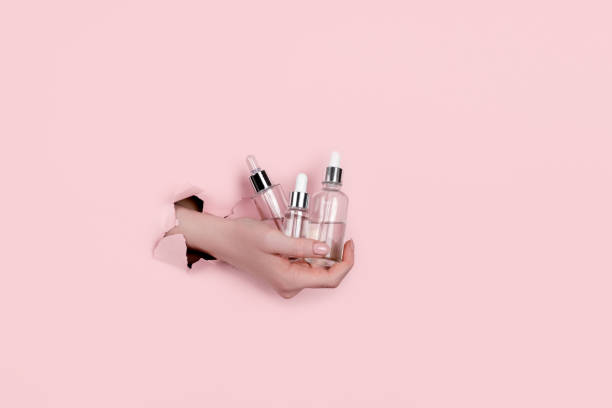 istock Female hand holding hyaluronic bottle from torn paper 1304299012