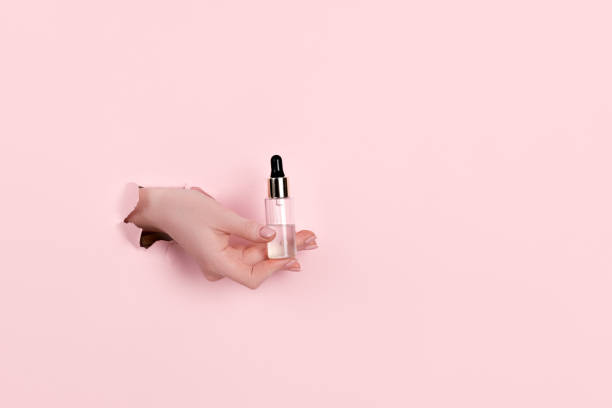 istock Female hand holding hyaluronic bottle from torn paper 1304299019