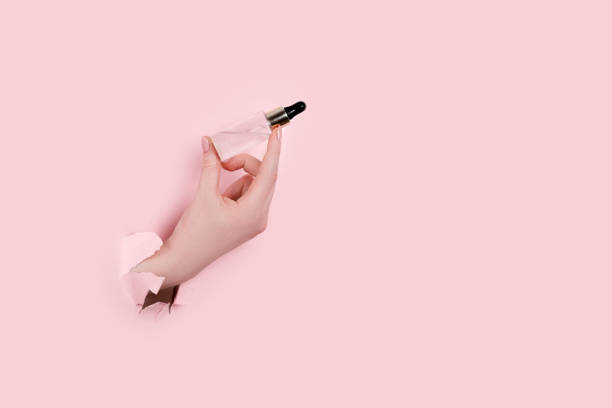istock Female hand holding hyaluronic bottle from torn paper 1304299022
