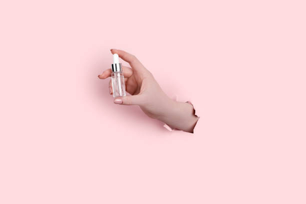 istock Female hand holding hyaluronic bottle from torn paper 1304299027
