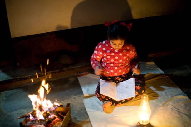 Rural girl studying next to fireplace and lantern at village