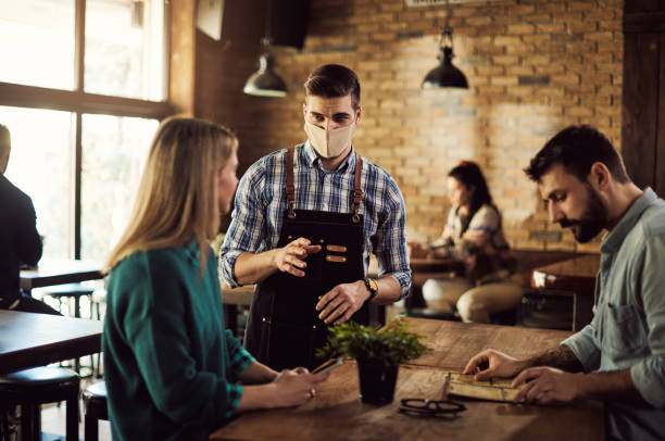 istock Waiter with protective face mask communicating with guests in a cafe. 1304304521