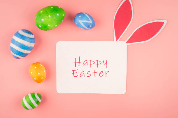 istock Bright Easter card with colorful eggs, paper rabbit ears on a pink background. Top view 1304304842