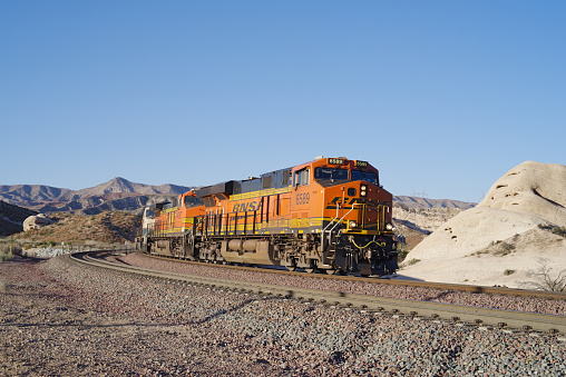 Cajon Pass, CA, USA - February 26, 2021: image showing a BNSF train traveling through the Mojave Desert. BNSF Railway is one of the largest freight railroad networks in North America.
